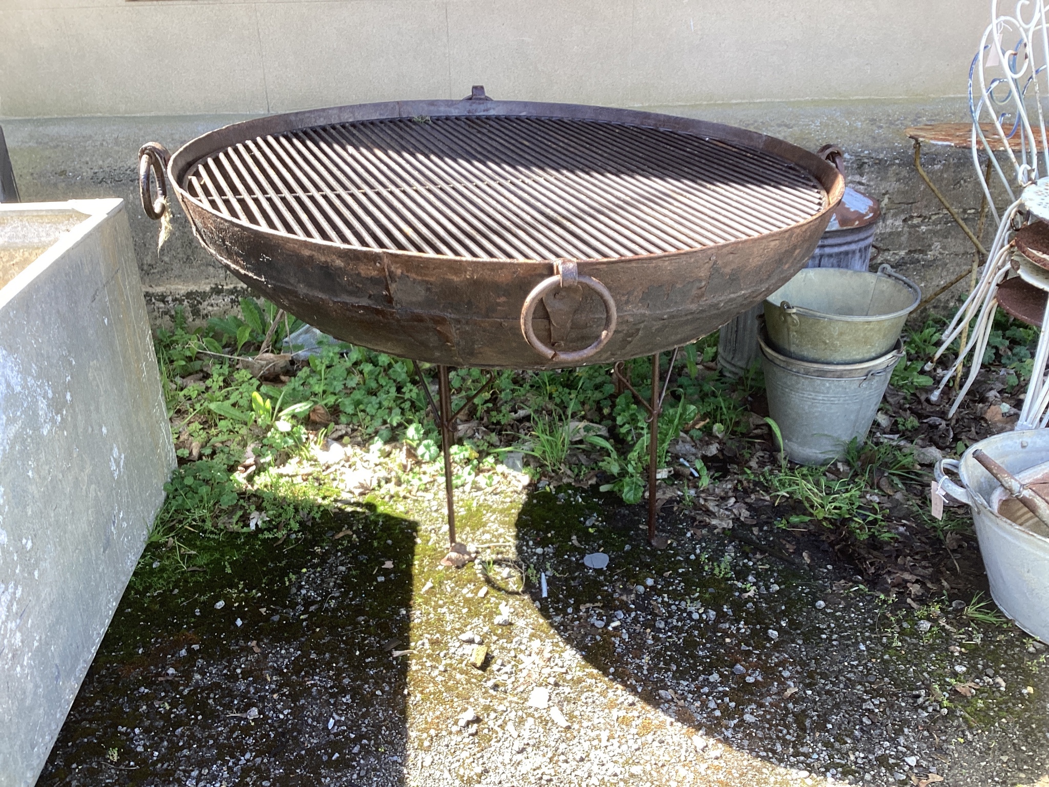 A large circular wrought and cast iron fire pit on stand diameter 133cm height 81cm